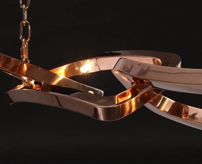 Close-up of the Elegant Industrial Gallery Pendant: a modern chandelier with interlocking, polished rose gold elements, illuminated against a black background.