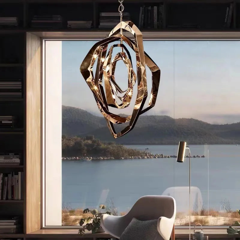 The Elegant Industrial Gallery Pendant in modern gold hangs before a large window with lake views, paired with a white chair and floor lamp. This LED pendant light enhances the serene setting with elegance.