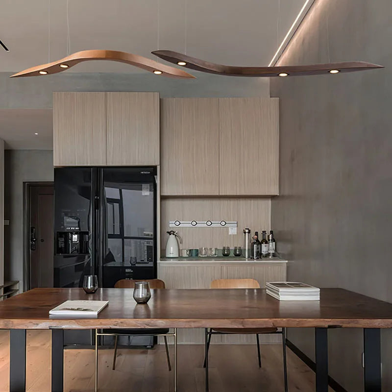 Modern kitchen with wood cabinets, a black refrigerator, a wooden dining table for two, and two Spiral Wood Pendant Lights hanging from the ceiling add an organic modern lighting touch to the space.