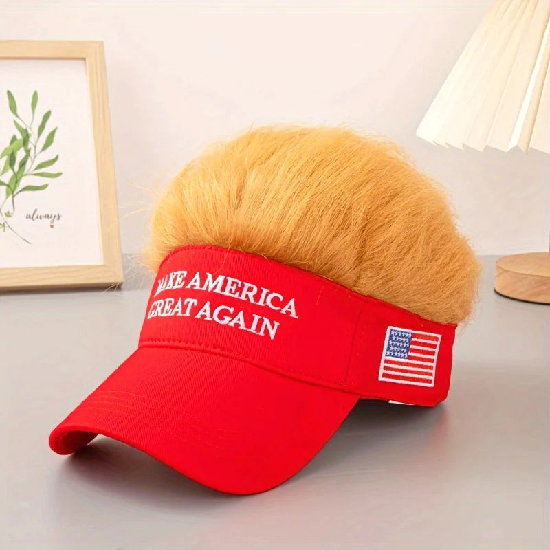 The Visor Cap - Make America Great Again, a red satirical cap with fake blond hair, sits near a framed photo and lamp—a true patriotic conversation starter.