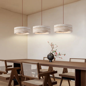 A Natural Stone Pendant Light hangs above a wooden dining table with four chairs; at the center of the table sits a black vase filled with branches and red berries.