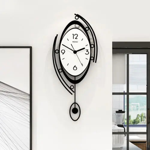 The Zen Arc Oval Statement Clock features a modern, abstract black and white design with a white face, black numbers and hands, and decorative curved lines, shown mounted on a white wall beside framed art.