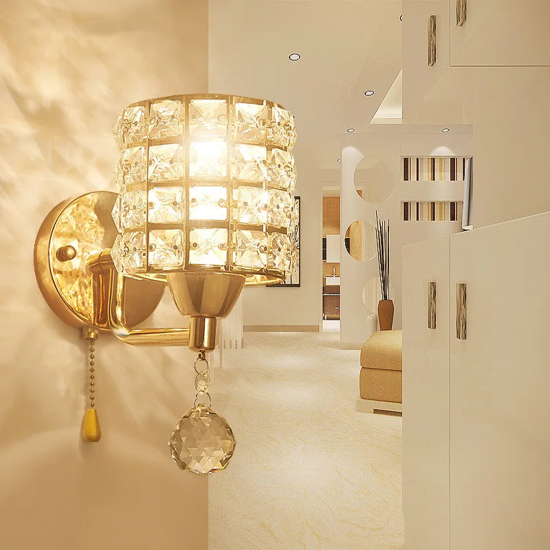 The Luxury Cylinder Wall Light, featuring a gold finish and dazzling shade, brightens a modern beige living space with contemporary decor, adding a touch of luxury.