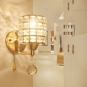 The Luxury Cylinder Wall Light, featuring a gold finish and dazzling shade, brightens a modern beige living space with contemporary decor, adding a touch of luxury.