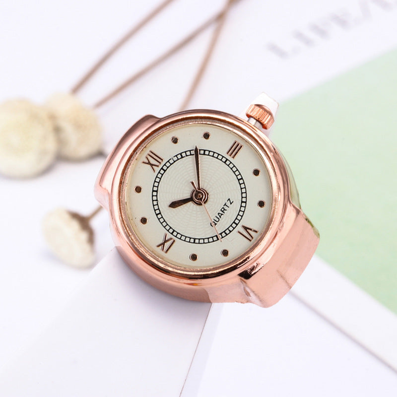 The Eternal Ring Watch, featuring a rose gold minimalist design with a white dial, black Roman numerals, and "QUARTZ" label, is showcased against a white and green backdrop.