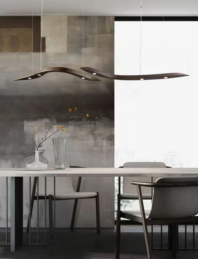 Modern dining area with abstract wall art, a white table, minimalist chairs, and the Spiral Wood Pendant Light adding organic modern style above a glass vase with slender branches.