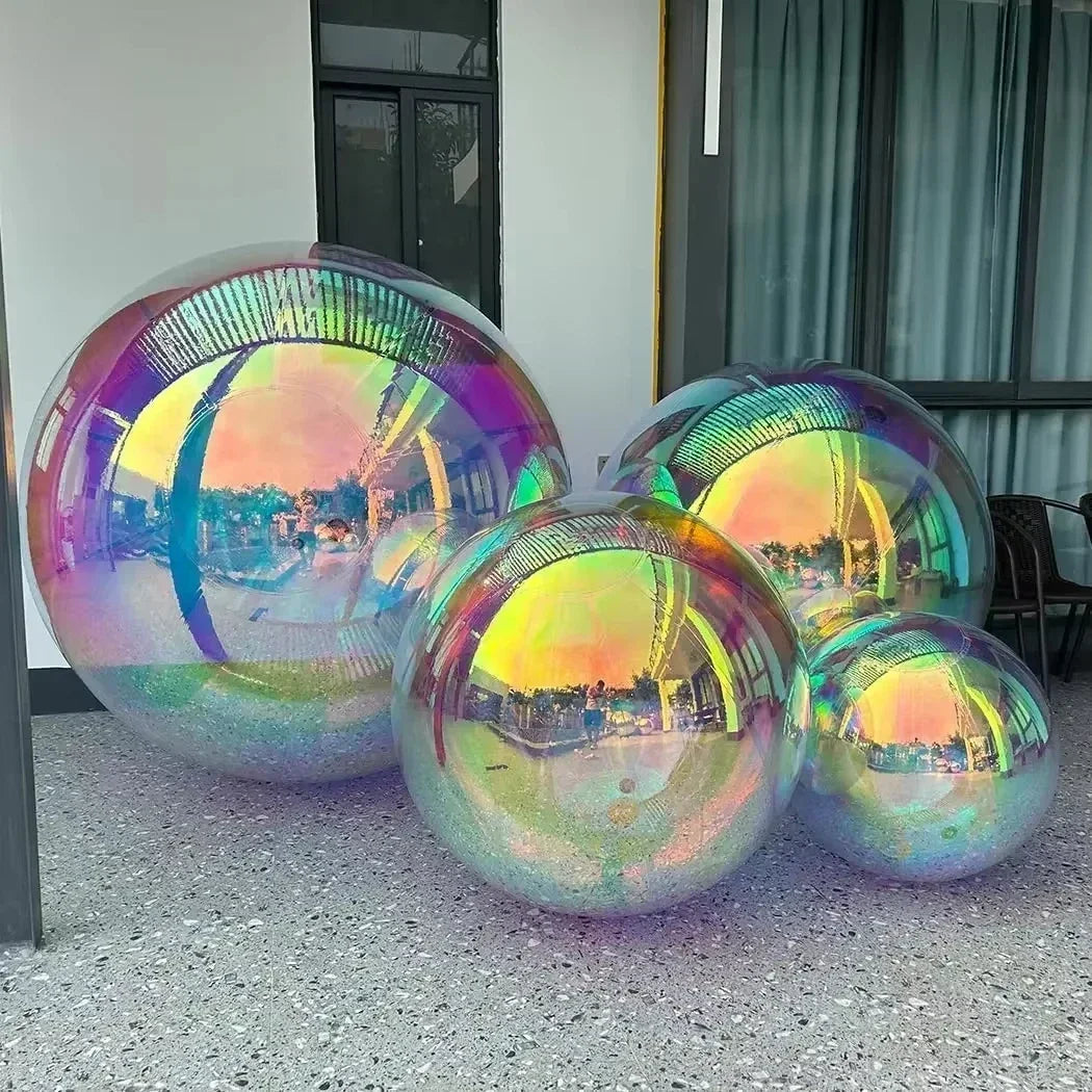 Four Inflatable Gazing Balls—large, iridescent, and reflective—are displayed on a terrazzo floor near a building with big windows and curtains, ideal for pool or garden decor.