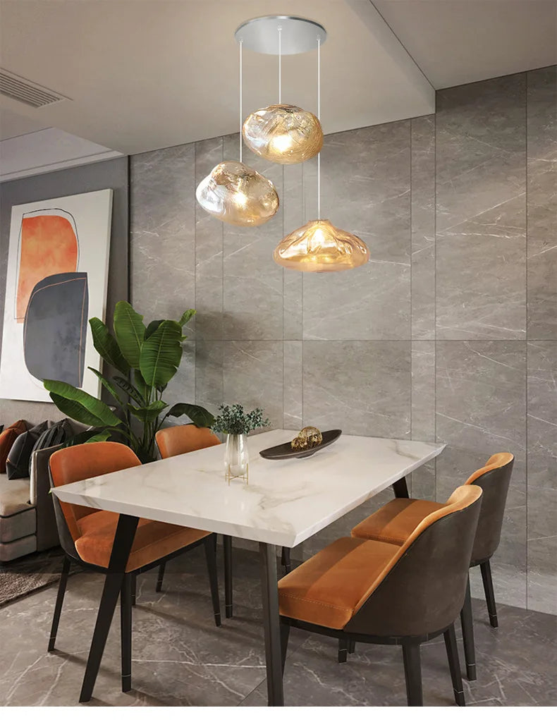 Modern dining area with a white marble table, four brown chairs, abstract wall art, a potted plant, and the Luxe Cloud Glass Pendant Light hanging above the table.