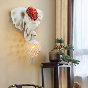 The 3D Elephant Wall Light, featuring a red ornamental cover and textured glass bulb, offers a unique ambiance. Positioned near a window and small table with plants, this wall-mounted decor piece effortlessly enhances any space.