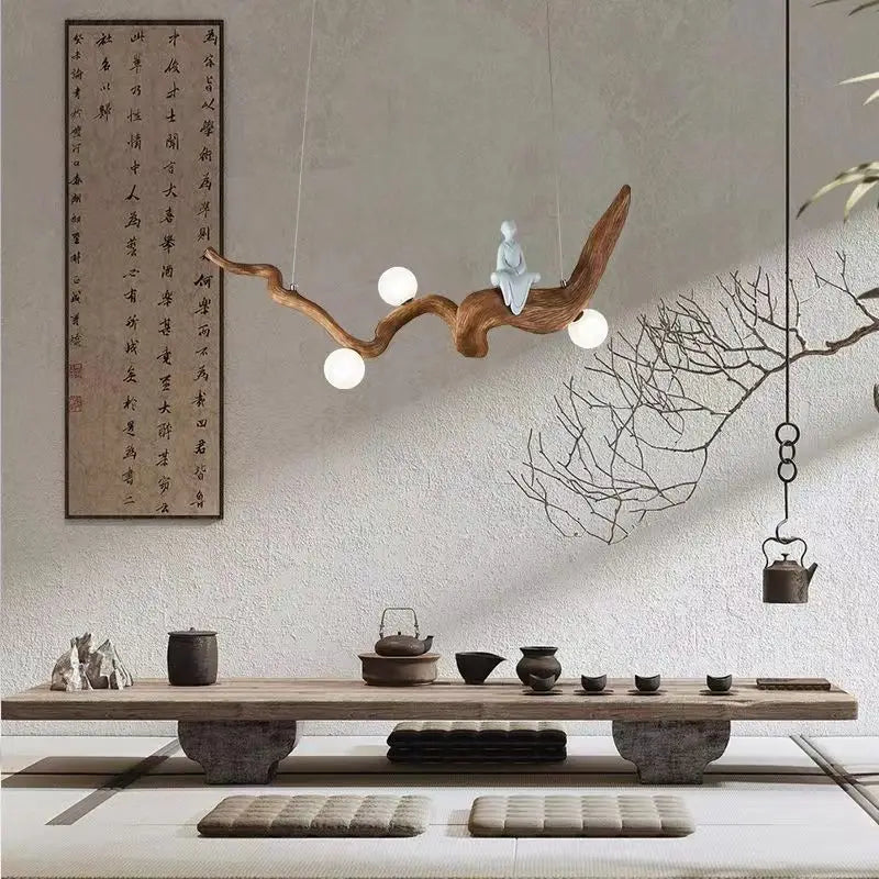 Minimalist decor with a Zen-Inspired Wooden Pendant Light, a tea set on the table, cushions, and a calligraphy scroll on the wall—all combine to create a serene zen aesthetic.