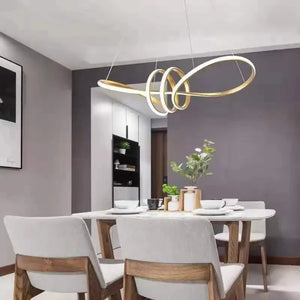 A modern dining room features a white table with four gray chairs. The Stylish Pendant Light hangs above, enhancing the minimalist design. A vase of flowers adorns the table, and a black-and-white picture decorates the wall.