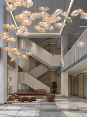 A modern, spacious lobby features the Luxe Cloud Glass Pendant Light as a sculptural centerpiece, marble flooring, minimal seating, and large windows flooding the space with natural light.