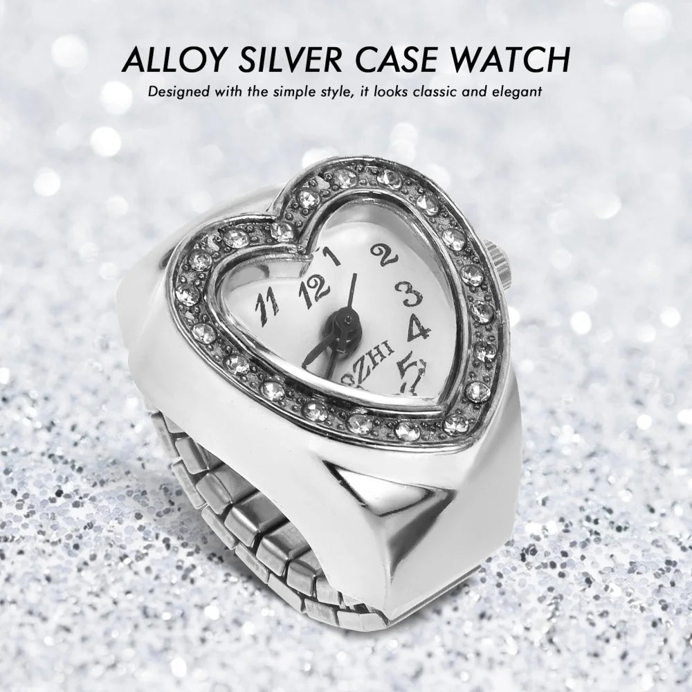 The Sweetheart Ring Watch, a heart-shaped accessory with rhinestones on the face displaying 11:12, rests on a glittery surface. Its romantic alloy silver case makes it perfect for rhinestone jewelry lovers.
