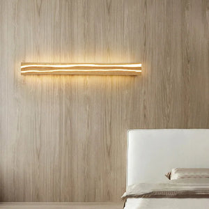 The Rectangle Wood Wall Light, a modern horizontal minimalist LED fixture, enhances a beige bedroom with wood paneling and a white bed, offering warm ambient lighting.