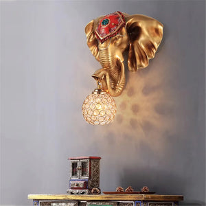 The 3D Elephant Wall Light, with its golden 3D elephant head design, casts a unique ambiance. Its ornate bulb illuminates the table below, creating an enchanting focal point.