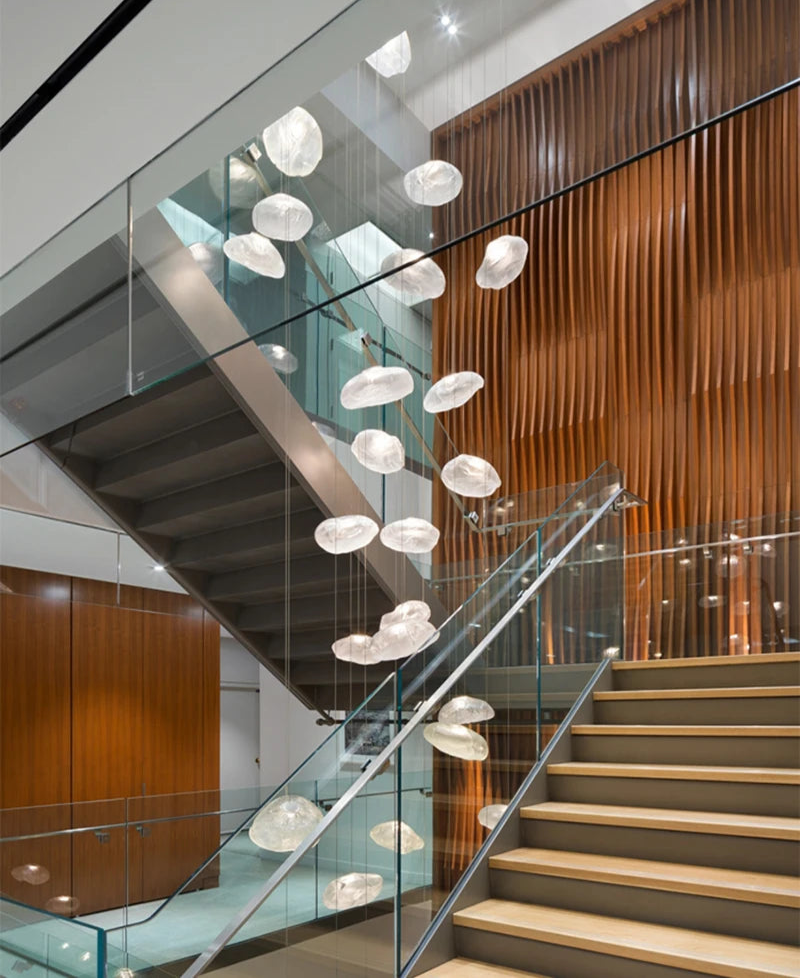 Modern staircase with glass railings, wood paneled walls, and a cluster of Luxe Cloud Glass Pendant Lights illuminating the open stairwell.