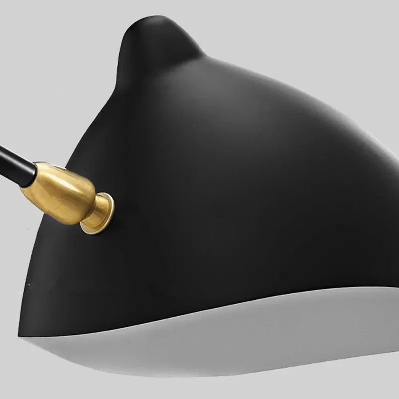Close-up of the Sleek Industrial Pendant Light, a black and white penguin-shaped fixture with a gold plug in its side, set against a plain gray background.
