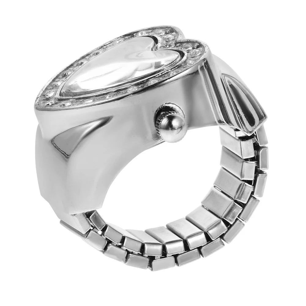 The Sweetheart Ring Watch features a silver heart-shaped design with gemstone accents and a flexible segmented band, blending rhinestone jewelry elegance with a stylish wristwatch look.