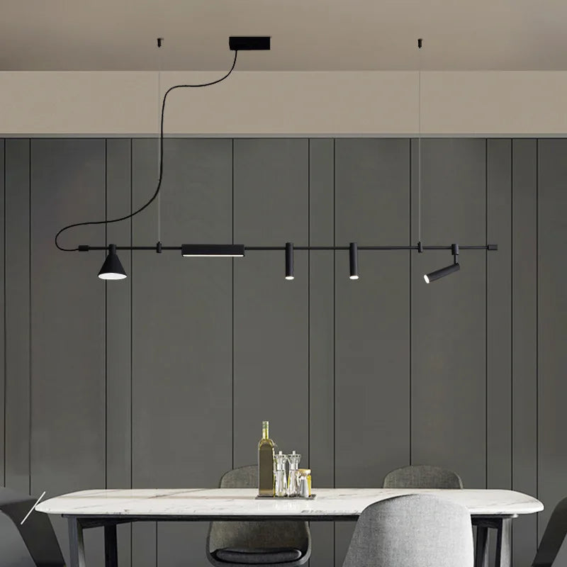 A modern dining room features a sleek black pendant light and the Modern Track Lighting with adjustable heads above a white table set with bottles and glasses. The look is completed with gray paneled walls and chairs for an industrial-inspired touch.