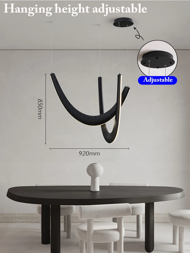 The Double Curve Wood Pendant Light, in modern black wood with adjustable hanging height, is installed above a dark oval dining table and four white chairs in a minimal dining room; measurements show the lamp size.