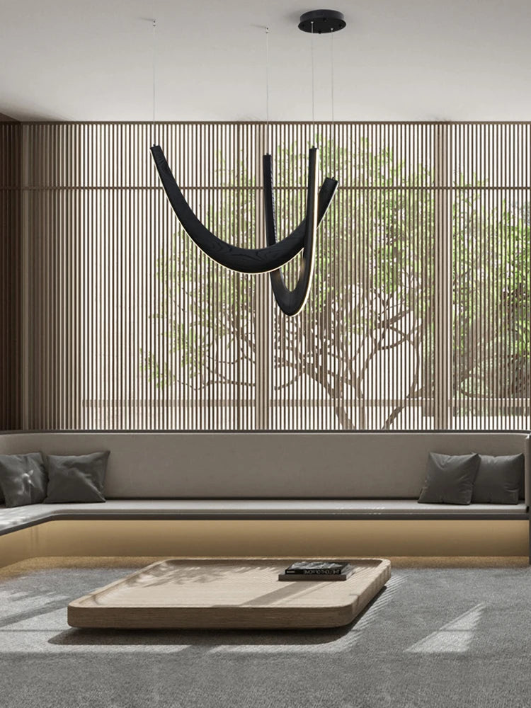 Modern minimalist living room featuring a low wooden table, built-in seating with gray cushions, a large window with vertical slats, and a striking Double Curve Wood Pendant Light.