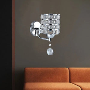 The Luxury Cylinder Wall Light with a square crystal shade and hanging accent brings luxurious lighting above an orange sofa set against a dark wall.