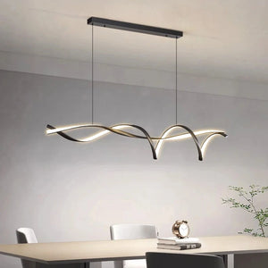 The Stylish Pendant Light blends nature-inspired design with elegance, featuring a wavy, intertwined look. It hangs gracefully over a minimalist dining table set with chairs and a small plant, ideal for modern living spaces.