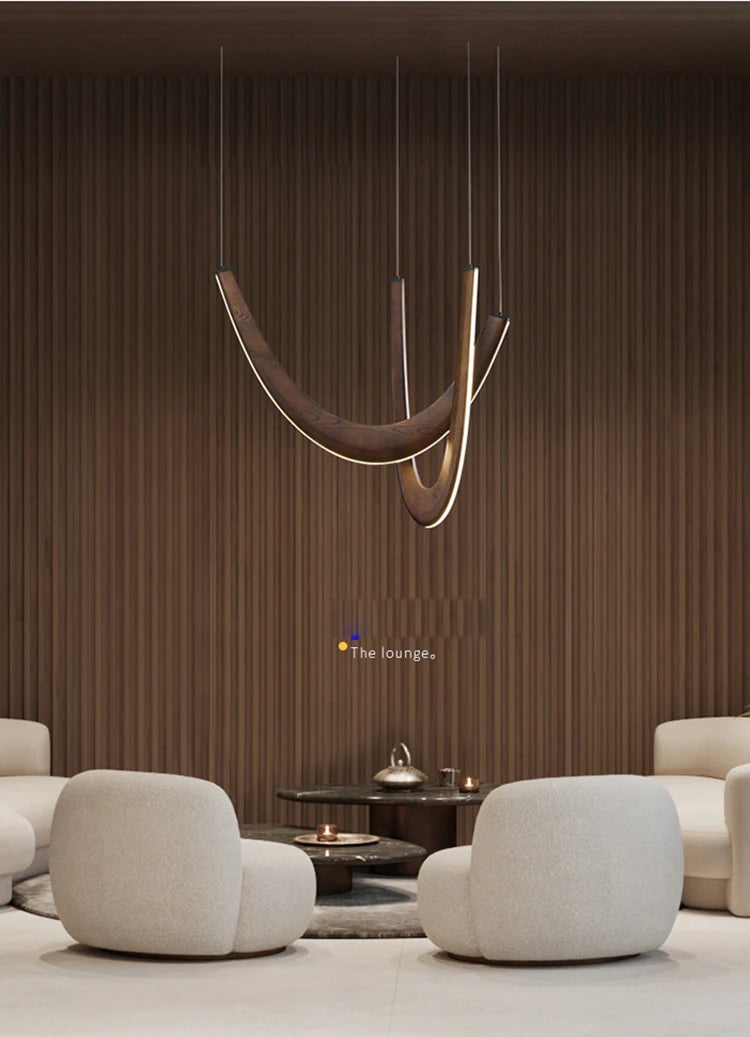 Modern lounge area featuring two white curved armchairs, a round coffee table, and the Double Curve Wood Pendant Light set against a wood-paneled wall.