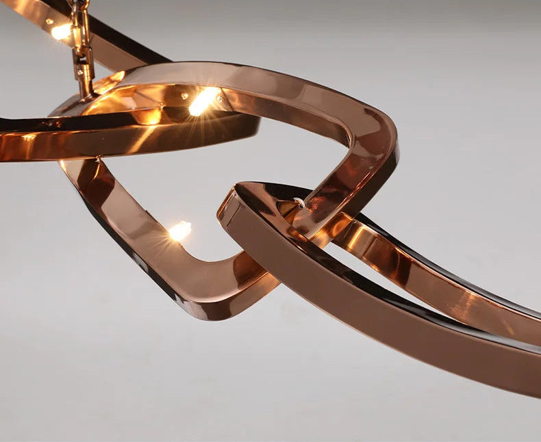 Close-up of the Elegant Industrial Gallery Pendant, featuring an abstract rose gold design with integrated LED lights glowing against a neutral background.