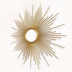 The Luxe Sunray Wall Mirror features a round gold sunburst frame with radiating metal rods, creating a stunning statement piece for any interior against a white background.