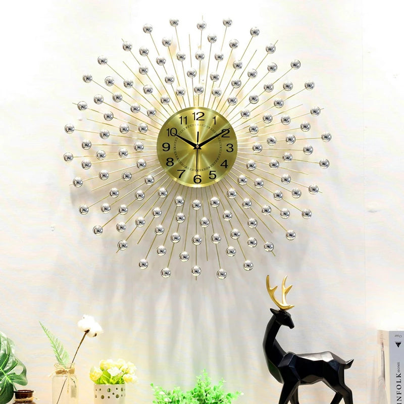 The Lux Radiance Starburst Wall Clock, inspired by mid-century modern design, features a gold sunburst style and is displayed above a black deer figurine and potted plants on a white wall.