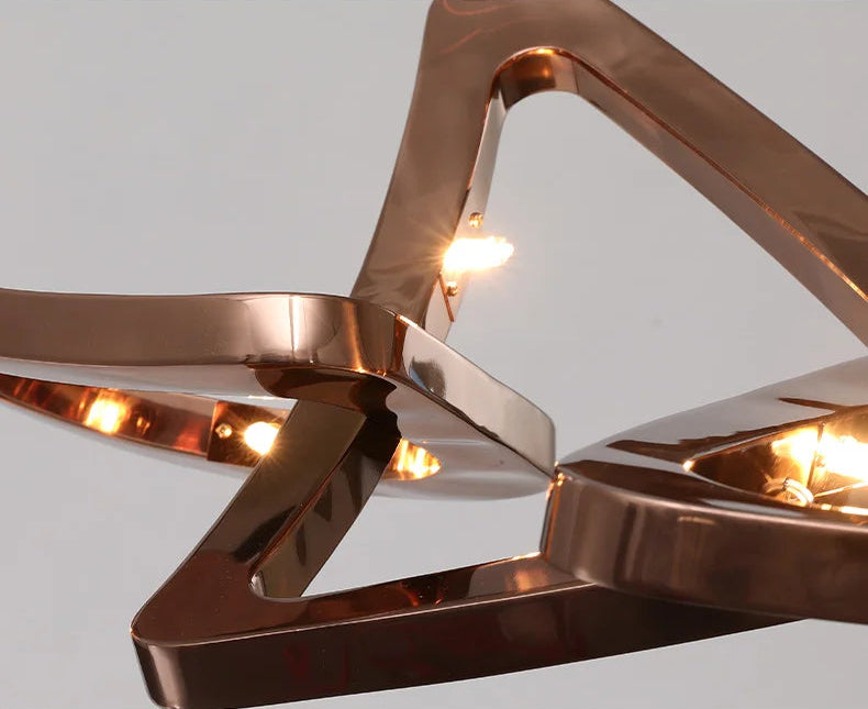 Close-up of the Elegant Industrial Gallery Pendant, featuring intersecting rose gold geometric shapes and visible LED bulbs for a bold, sculptural look.