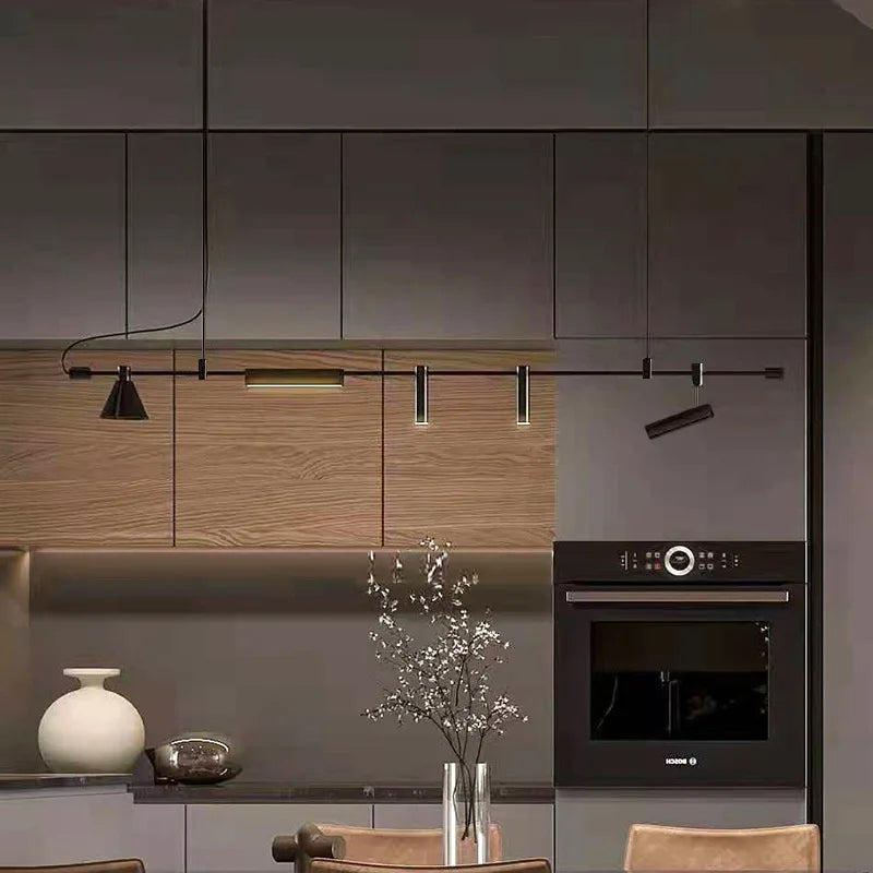 A modern kitchen interior features wooden cabinets, a built-in oven, and the Modern Track Lighting in black with adjustable heads. A vase with branches and a decorative white pot adorn the counter.