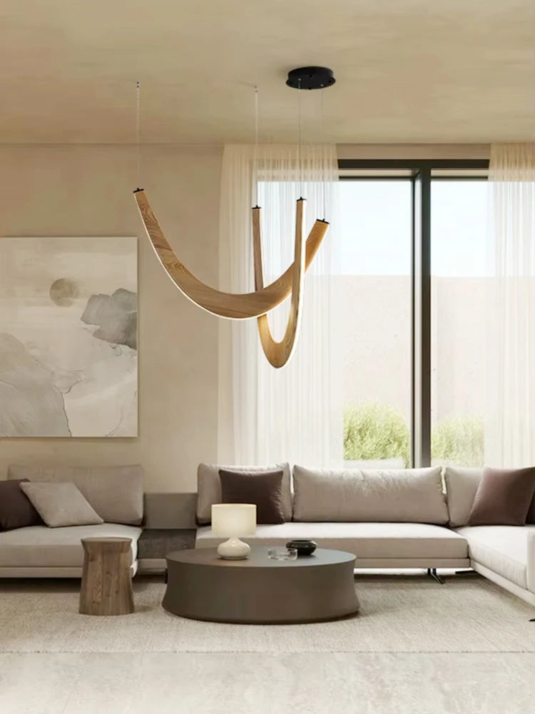 Modern living room with neutral tones, featuring the Double Curve Wood Pendant Light, a round coffee table, white sofas, sheer curtains, and abstract wall art.