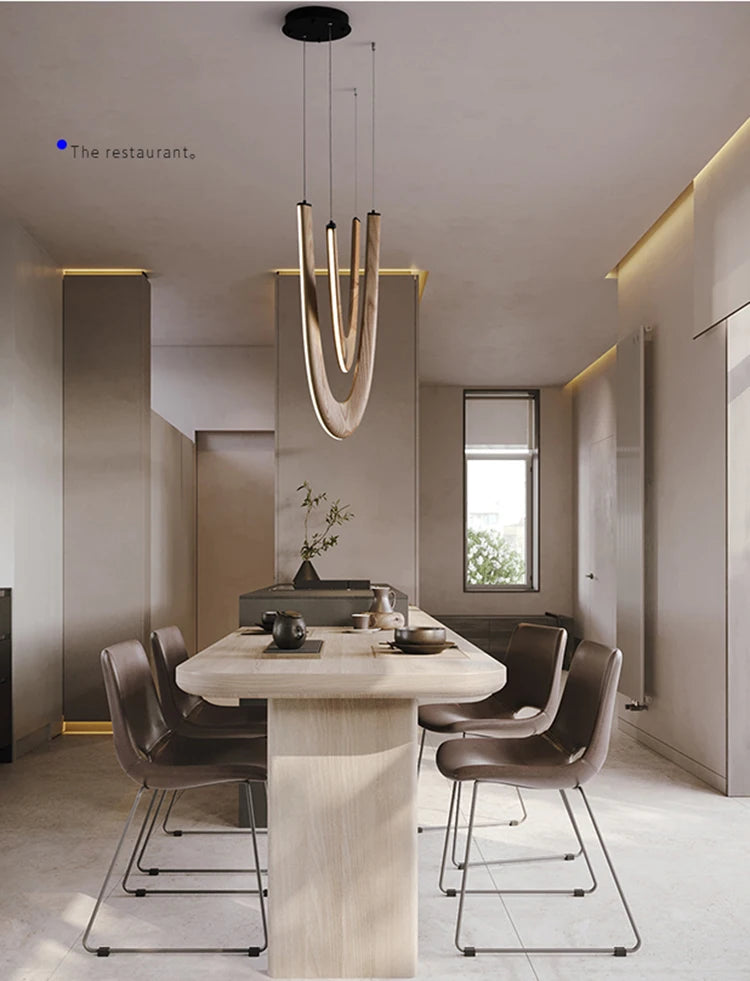 A modern dining room with a light wood table, six brown chairs, and neutral-toned walls is illuminated by the Double Curve Wood Pendant Light, adding an elegant touch overhead.