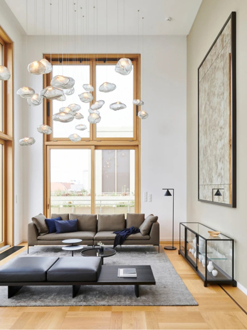 Modern living room with high ceilings, large windows, a gray sofa, black coffee tables, Luxe Cloud Glass Pendant Lights, a floor lamp, and a large framed artwork on the wall.