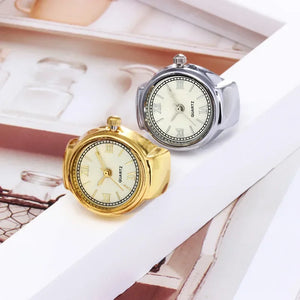 Two Eternal Ring Watches, one gold and one silver, feature round faces with Roman numerals and "QUARTZ" labels. Both ring-shaped jewelry timepieces are displayed on a white frame.
