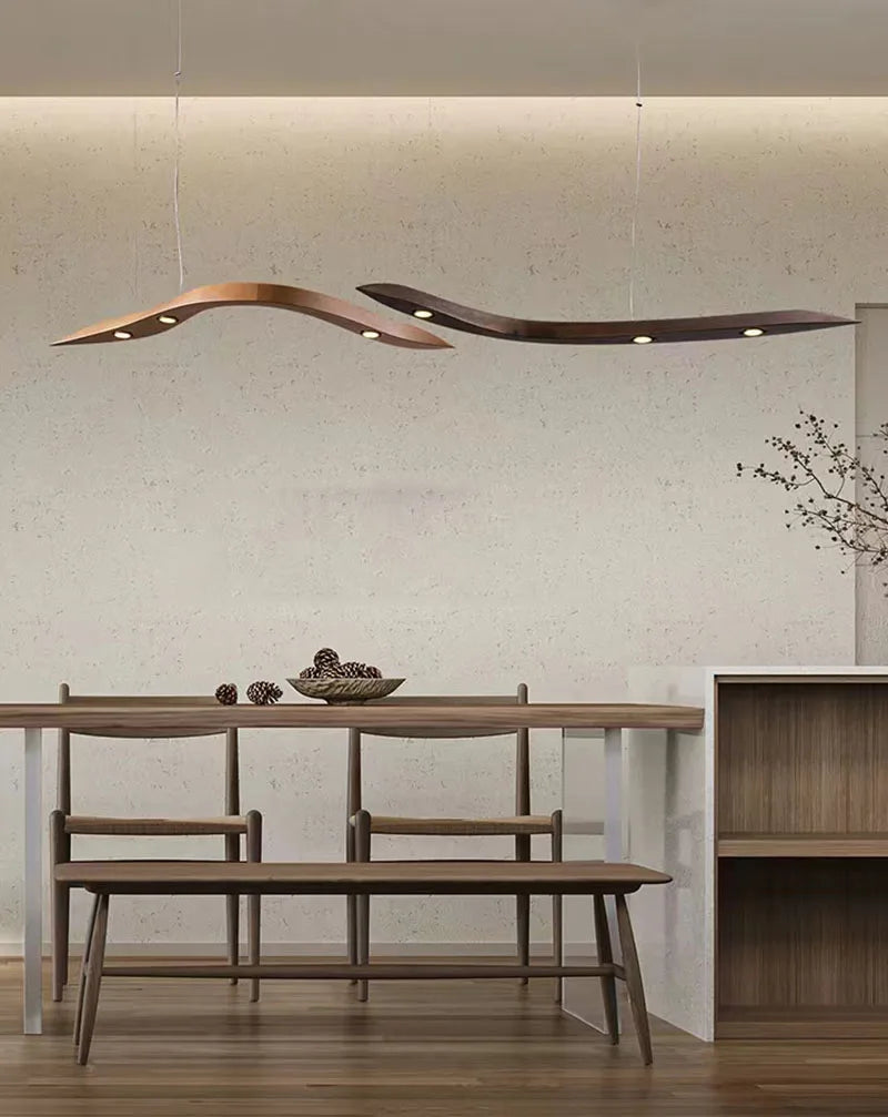 Modern dining area featuring a wooden table, benches, decorative ceramics, a minimalist plant, and the Spiral Wood Pendant Light for stylish modern home lighting against a light-colored wall.