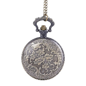 The Skeleton Pocket Watch features an ornate floral pattern engraved on its closed metal cover and hangs elegantly from a chain.