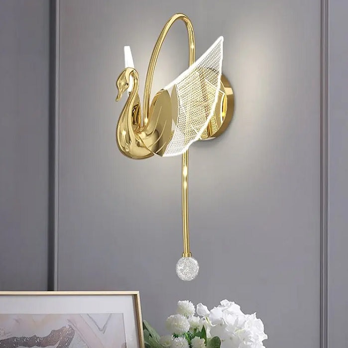 A Swan Wall Light, featuring intricate gold wing details and mounted on a gray wall, adds a touch of elegance to the room. Below it, white flowers in a vase complete the sophisticated ambiance.