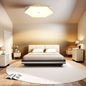 A modern bedroom features a large bed, two nightstands with lamps, a round rug, and an open book on the floor. Soft lighting, enhanced by the Natural Stone Ceiling Light, blends minimalist decor with subtle wabi-sabi lighting elements to create a serene and inviting atmosphere.