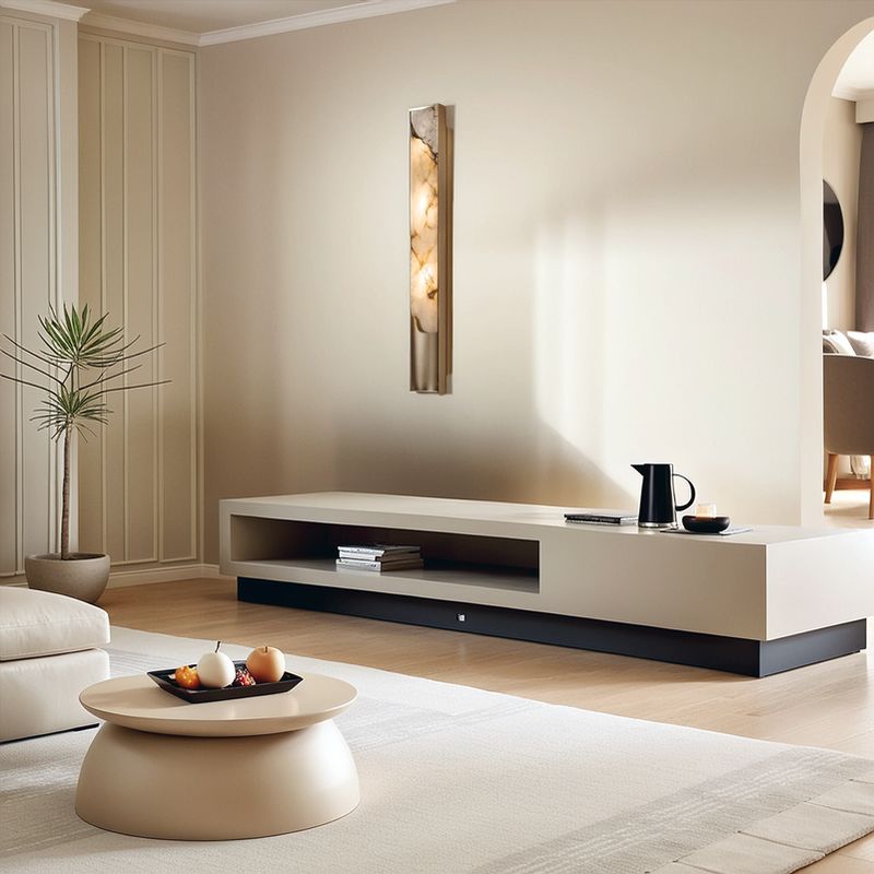 Modern living room with a low beige TV stand, round coffee table, potted plant, and wall art in neutral tones and minimalist decor. The Luxury Marble Wall Sconce introduces an elegant touch to the space, enhancing its sophisticated atmosphere.