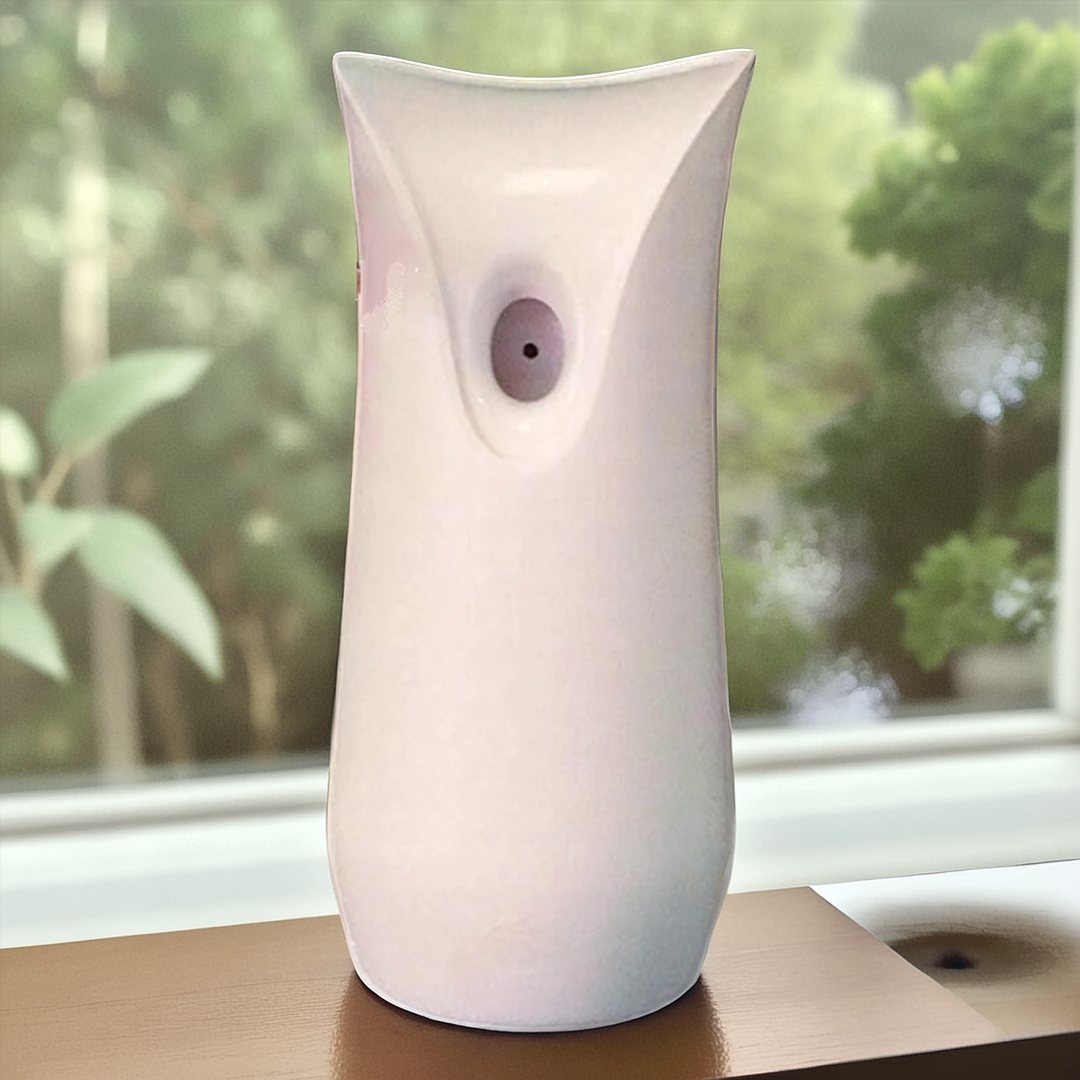 The White Decorative Display SpyCam sits discreetly on a wooden surface, resembling an automatic air freshener. Its covert design blends seamlessly with green foliage and a window in the background, perfect for clandestine surveillance operations.