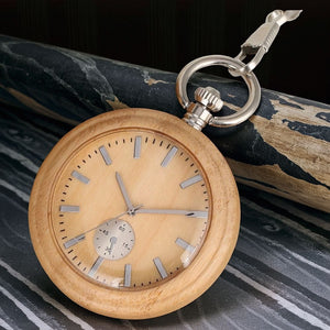 The Wood Pocket Watch, crafted from solid wood with silver hour markers and hands, rests on a black and gray marble surface.