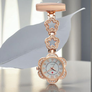The Luxe Fob Pocket Watch in rose gold features a floral design with crystal accents, showcased against a white leaf background.