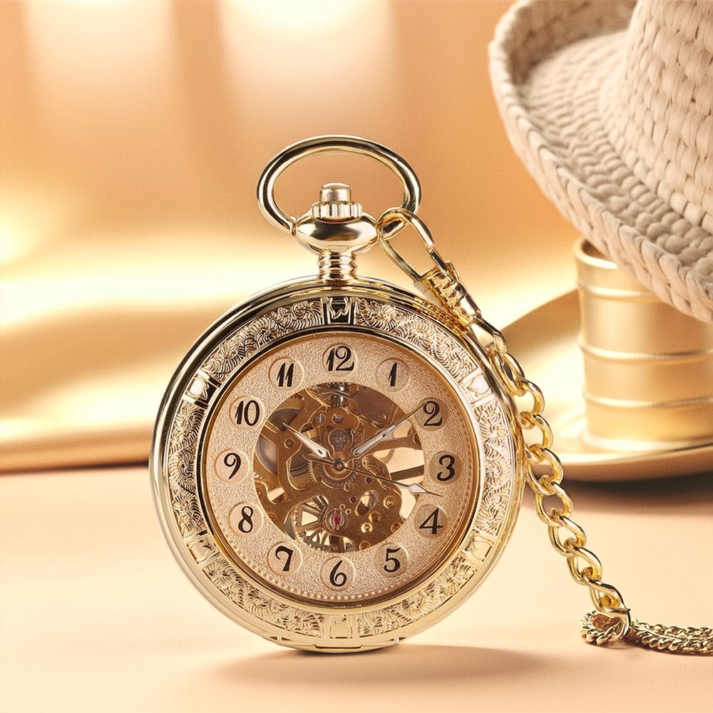 The Premium Golden Pocket Watch, featuring a skeleton dial and ornate details, is attached to a golden chain and rests on a beige surface near a woven hat.
