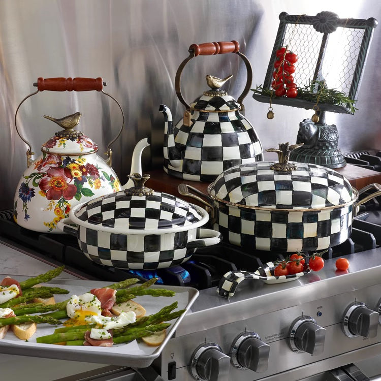 A Vintage Black and White Kettle with a sparrow-shaped knob is displayed on the stove alongside black and white checkered cookware, with a tray of asparagus appetizers in the foreground.
