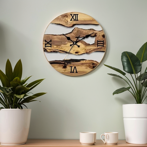 A Wood Circular Wall Clock featuring a natural wood design and Roman numerals hangs above two potted plants on a light-colored wall, enhancing the décor with an organic touch.