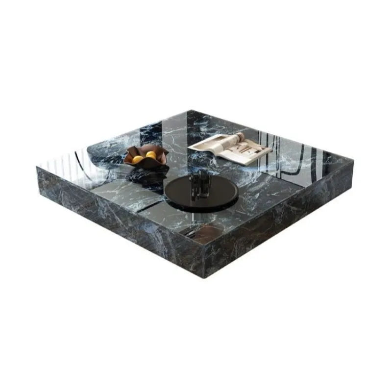 The Modern Luxe Coffee Table, a square black marble piece with a glossy finish, is ideal for modern interiors and holds a black tray, a decorative fruit bowl, and a folded newspaper.
