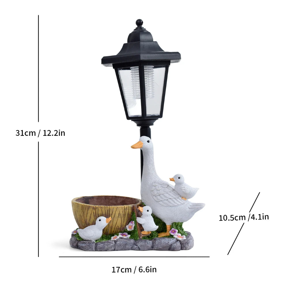 Bring charm to your cottage garden with the Solar Goose Lamp—this delightful decor piece features a goose with two goslings, a small planter, and vibrant flowers, measuring 31cm tall, 17cm wide, and 10.5cm deep.